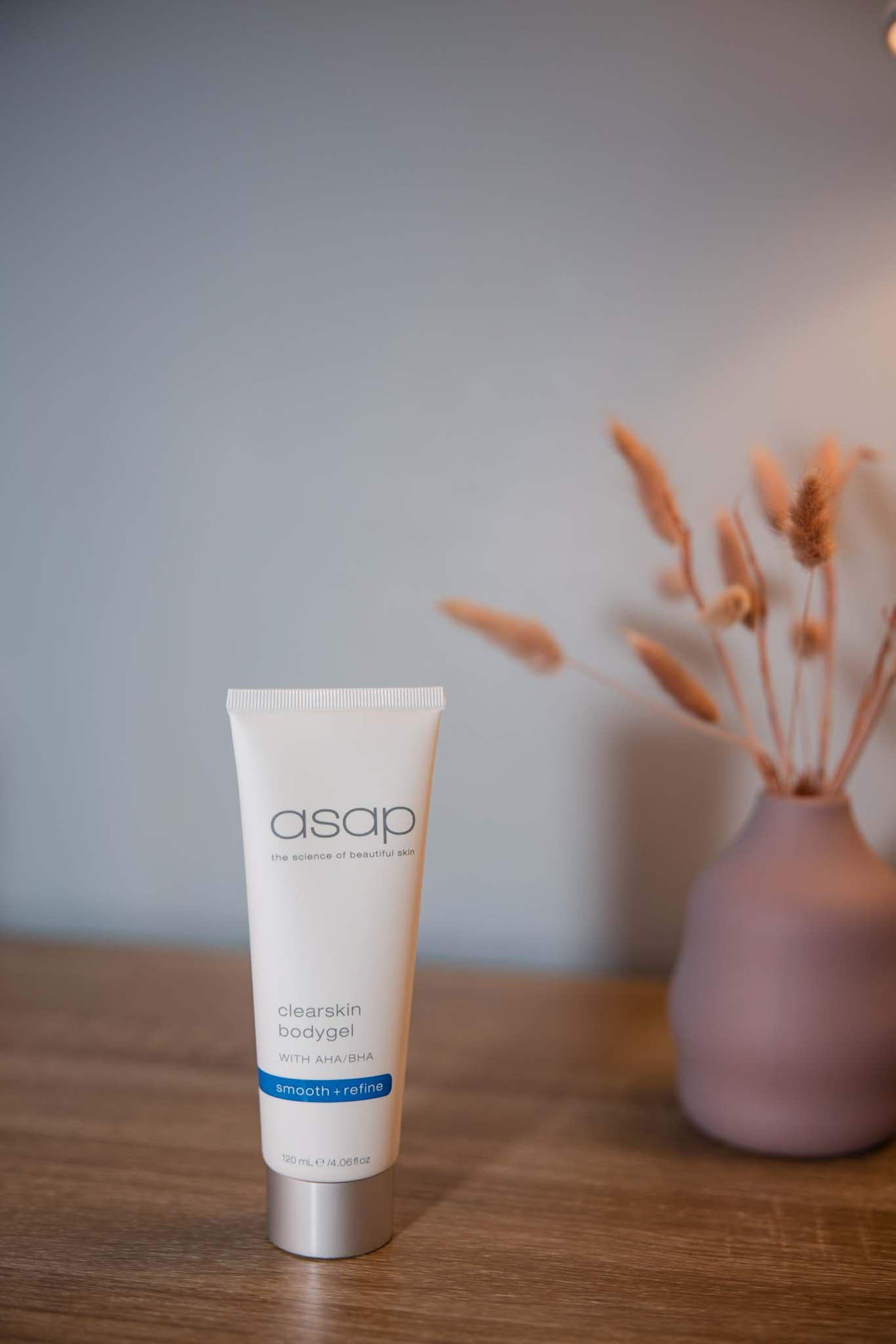 asap Clearskin Bodygel on a wooden table with a pink vase in the background